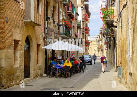 Menschen sitzen auf der Außenterrasse eines Restaurants in den Straßen der Altstadt von Puente La Reina, Spanien Stockfoto