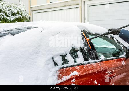 Schneeräumung von der Windschutzscheibe. Reinigung und Reinigung des Autos von Schnee an einem Wintertag. Stockfoto