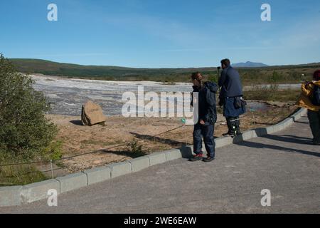 Ein paar Touristenattraktionen, die Markierung für den ruhenden Großen Geysir Islands an den östlichen Hängen des Laugarfjalls. Stockfoto