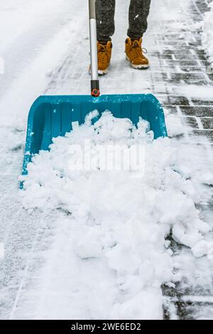 Schneeräumung von der Straße im Winter mit Schaufel nach Schneesturm. Reinigung des Gehwegs von Schnee an einem Wintertag. Stockfoto