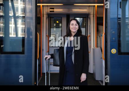 Lächelnde Frau mit Koffer im Zug Stockfoto