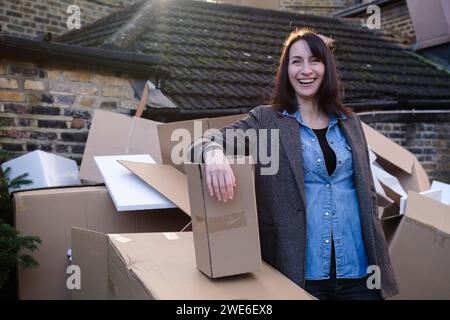 Glückliche Frau, die neben Pappkartons steht Stockfoto