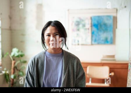 Lächelnder Künstler im Strickpullover, der in der Kunstwerkstatt steht Stockfoto