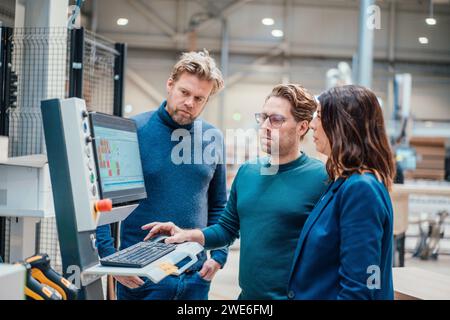 Geschäftsmann, der Computer benutzt und mit Kollegen aus der Industrie diskutiert Stockfoto