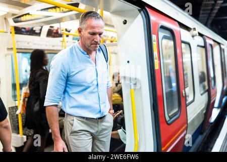 Geschäftsmann, der an der U-Bahn-Station aus dem Zug aussteigt Stockfoto