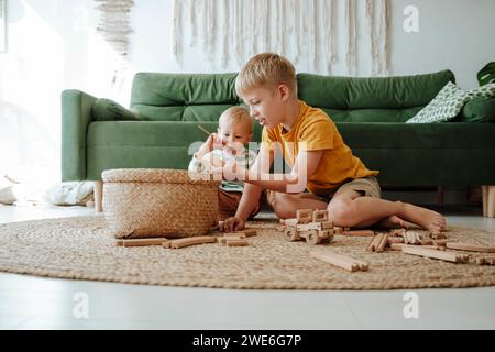 Zwei Brüder spielen mit hölzernen Zügen im Wohnzimmer zu Hause Stockfoto
