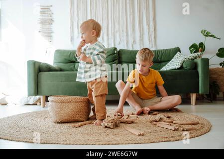 Zwei Brüder spielen mit hölzernen Zügen im Wohnzimmer zu Hause Stockfoto