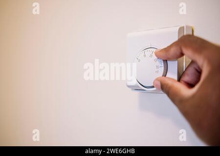 Hand-of-man-Einstellung der Temperatur des Thermostats zu Hause Stockfoto