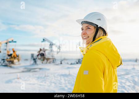 Lächelnder junger Ingenieur, der im Winter auf dem Ölförderfeld einen Helm trägt Stockfoto