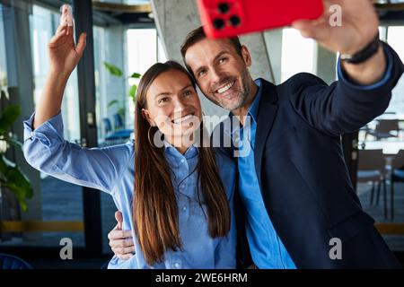 Glücklicher Geschäftsmann, der ein Selfie mit einem Kollegen im Büro macht Stockfoto