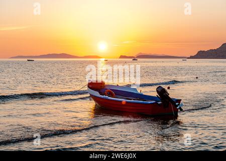 Griechenland, Ionische Inseln, Arillas, Motorboot am Strand bei Sonnenuntergang Stockfoto