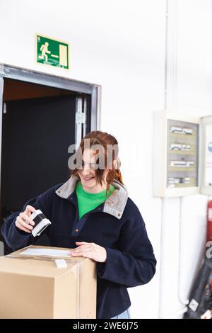 Glückliche Lieferfrau stempelt das Paketdokument im Verteilerlager Stockfoto