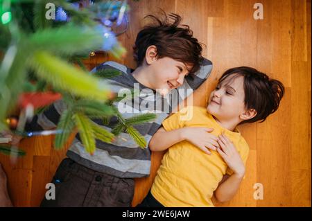Glückliche Brüder, die zu Hause unter dem Weihnachtsbaum liegen Stockfoto