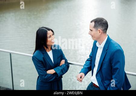 Lächelnde Geschäftsfrau, die mit einem Kollegen in der Nähe des Geländes spricht Stockfoto