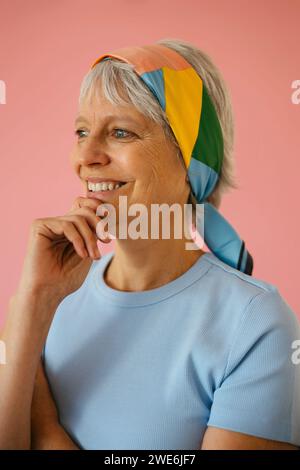 Nachdenkliche reife Frau mit Hand am Kinn vor rosa Hintergrund Stockfoto