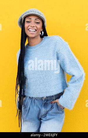 Glückliche Frau mit Händen in Taschen, die einen Pullover trägt Stockfoto