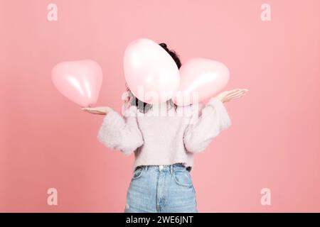 Frau spielt mit Ballons vor rosa Hintergrund Stockfoto