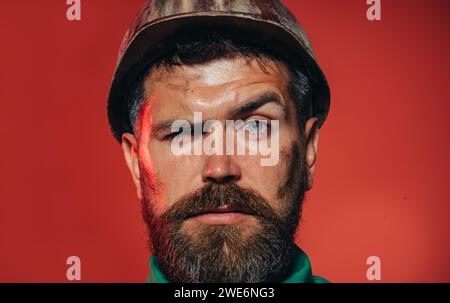 Nahaufnahme eines mechanischen oder industriellen Arbeiters mit Schutzhelm. Ernsthafter bärtiger Mann im Bauhelm. Schöner Ingenieur, Architekt Stockfoto