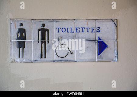Ein Schild mit Keramikfliesen führt Touristen zu den Toiletten im French Quarter von New Orleans, Louisiana Stockfoto