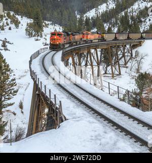 Im Winter überqueren Züge, die Kohlewagen in Richtung mullan transportieren, einen Höhenruder in der Nähe von austin, montana Stockfoto