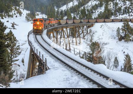 Im Winter überqueren Züge, die Kohlewagen in Richtung mullan transportieren, einen Höhenruder in der Nähe von austin, montana Stockfoto