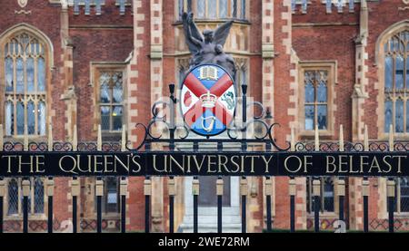 Reich verziertes schmiedeeisernes Tor mit dem Namen und dem Wappen der Queen's University in Belfast, Nordirland. Stockfoto