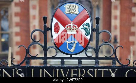 Kunstvolles schmiedeeisernes Tor mit dem Namen und dem Wappen der Queen's University in Belfast, Nordirland. Stockfoto