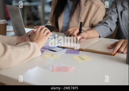 Zugeschnittene Aufnahme eines kreativen Grafikdesignerteams, das gemeinsam im Büro arbeitet, über ein neues Projekt diskutiert, ein Brainstorming erstellt und geplant hat. UX-BENUTZEROBERFLÄCHE Stockfoto