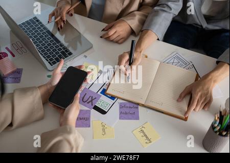 Zugeschnittene Aufnahme eines kreativen Grafikdesignerteams, das gemeinsam im Büro arbeitet, über ein neues Projekt diskutiert, ein Brainstorming erstellt und geplant hat. UX-BENUTZEROBERFLÄCHE Stockfoto