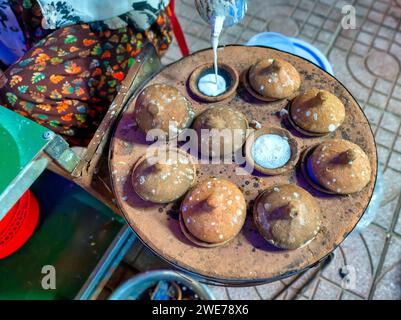Mini-Pfannkuchen werden aus Reismehl hergestellt, das in eine gebackene Tonform gebacken wird. Der Kuchen wird mit Fischsauce und Gemüse serviert. Lieblingsessen auf der Straße Stockfoto