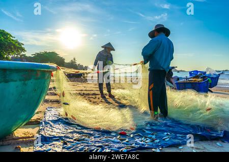 Fischmarkt Session Seeszene Menschen versammelten sich im Korb Fischverkauf, anstrengende Ruderfischer brachten an Land Fischerdorf in Phan Thiet Stockfoto