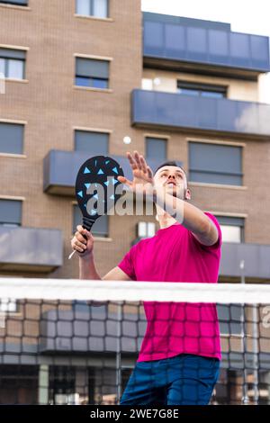 Ein Mann, der sich darauf vorbereitet, den Ball in Pickleball zu schießen. In Pickleball ist es verboten, mit irgendwelchen zu volley (Ball schlagen, ohne vorher den Boden zu berühren) Stockfoto