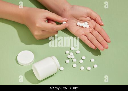 Gesundheitskonzept mit vielen weißen Tabletten auf dem Hintergrund und in der Hand mit einer Arzneimittelflasche. Jedes Medikament hat einen Zweck Stockfoto