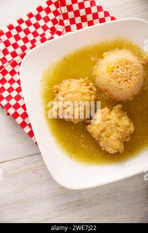 Koteletts aus gehacktem Hühnerfleisch in Teigeiern gebraten, in Mexiko bekannt als Tortitas de Pollo, gebadet mit grüner Sauce und begleitet von Reis. Tradition Stockfoto