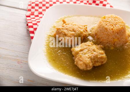 Koteletts aus gehacktem Hühnerfleisch in Teigeiern gebraten, in Mexiko bekannt als Tortitas de Pollo, gebadet mit grüner Sauce und begleitet von Reis. Tradition Stockfoto