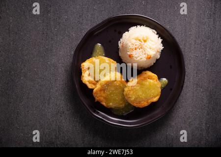 Koteletts aus gehacktem Hühnerfleisch in Teigeiern gebraten, in Mexiko bekannt als Tortitas de Pollo, gebadet mit grüner Sauce und begleitet von Reis. Tradition Stockfoto