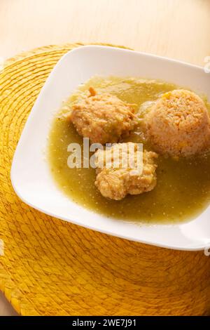 Koteletts aus gehacktem Hühnerfleisch in Teigeiern gebraten, in Mexiko bekannt als Tortitas de Pollo, gebadet mit grüner Sauce und begleitet von Reis. Tradition Stockfoto