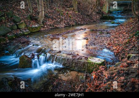 Lange Exposition des Flusses Leutra im Bezirk Jena West, der im Spätherbst durch einen kleinen Park fließt, Jena, Thüringen, Deutschland Stockfoto