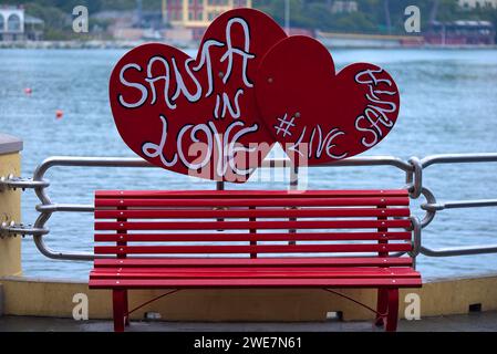Rote Parkbank, dahinter steht die Schrift: Santa in Love, Father Christmas in Love, am Hafen von Portofino, Italien Stockfoto