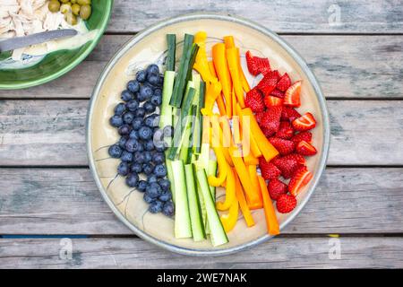 Gesunder Teller mit Obst und Gemüse auf einem Tisch im Freien, der einen Sommerabend genießt. Stockfoto