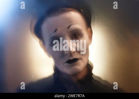Unscharfes Nahporträt eines MIME-Performers, der die Kamera im Spotlight der Bühne, im Kopierraum betrachtet Stockfoto
