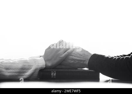 Christ betet mit den Händen auf der Bibel, Großmutter, Enkelin und Tochter Hände halten und beten Glauben, Evangelisation und Anbetung Stockfoto