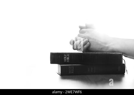 Christliche Silhouette betet und betet mit Händen auf heiliger Bibel, Religion, Glauben und Glaubensgrundlagen Stockfoto