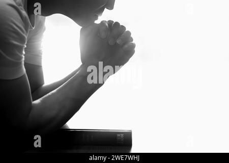 Heiliges Bibelbuch und christliche Silhouette beten und anbeten, Religion, glaube und Glaubenshintergrund Stockfoto