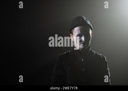 Minimales Porträt von trauriger Mime auf der Bühne in Konturbeleuchtung vor schwarzem Hintergrund, Kopierraum Stockfoto