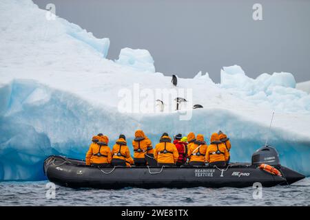 Eine Gruppe von Touristen an Bord eines Tierkreislaufs beobachtet adelie-Pinguine auf einem Eisberg Stockfoto