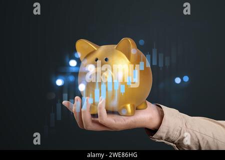 Ein Geschäftsmann, der eine goldene Sparkasse mit einer virtuellen Aktienbörse mit farbigem Hintergrund hält. Konzept der Finanzinvestitionen Stockfoto