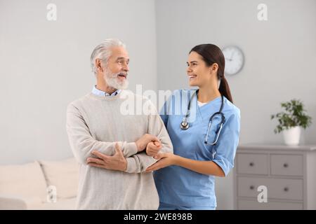 Lächelnde Krankenschwester, die ältere Patienten im Krankenhaus unterstützt Stockfoto