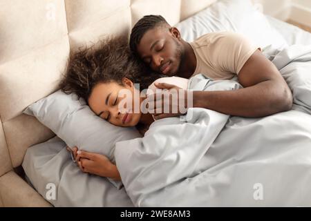 Ein junges schwarzes Paar, das zu Hause im Familienbett schläft Stockfoto