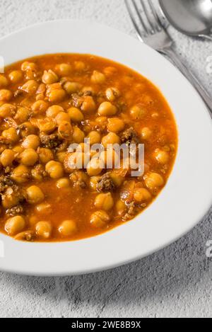 Kichererbseneintopf mit Hackfleisch auf einem weißen Porzellanteller auf einem Steintisch Stockfoto